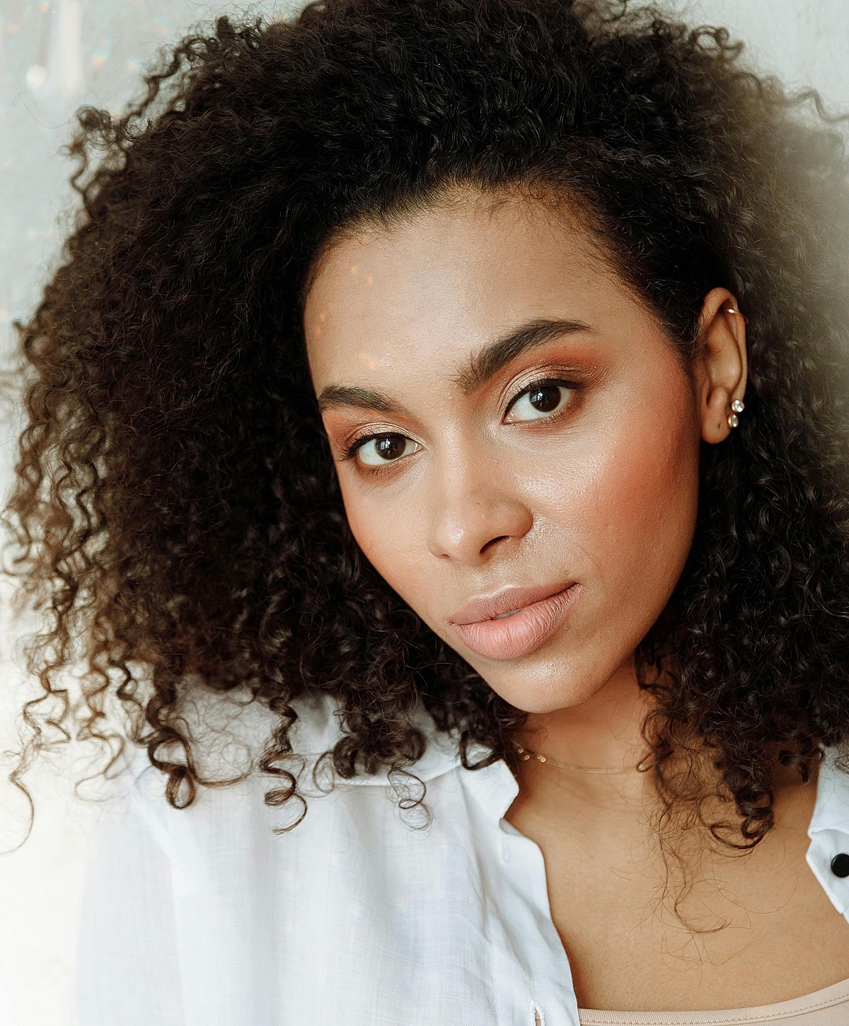 Woman with curly hair, natural makeup close-up.