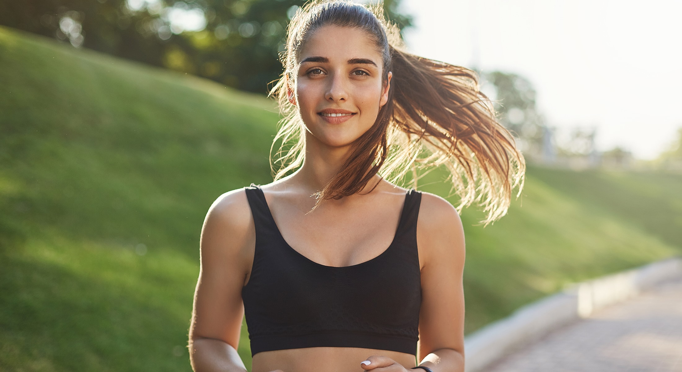 Smiling woman jogging outdoors in athletic wear.