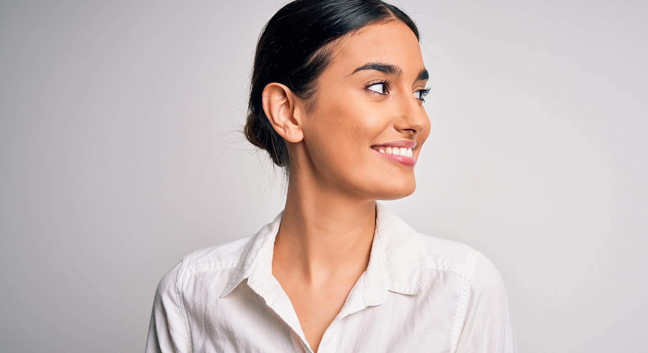 Smiling woman in a white shirt, profile view.
