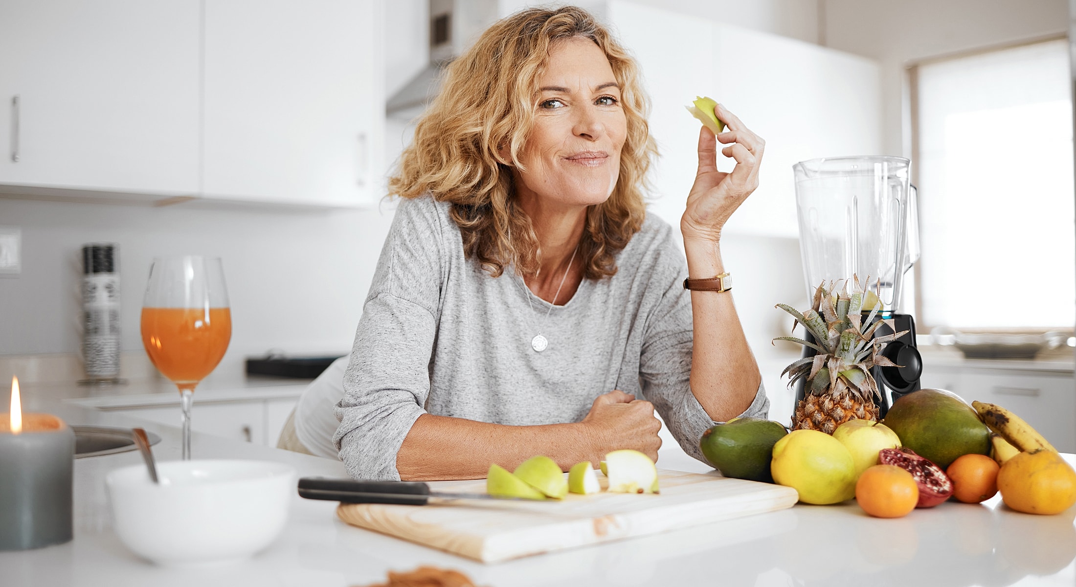 Woman enjoying fresh fruit in modern kitchen.