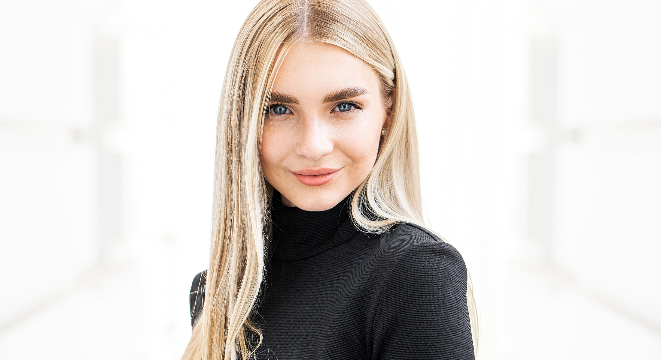 Smiling woman with long blonde hair in black top.